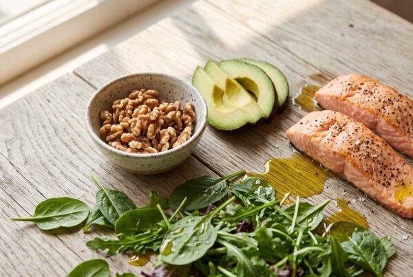 Heart-healthy foods including walnuts, olive oil, leafy greens, and salmon supporting a naturopathic approach to cholesterol